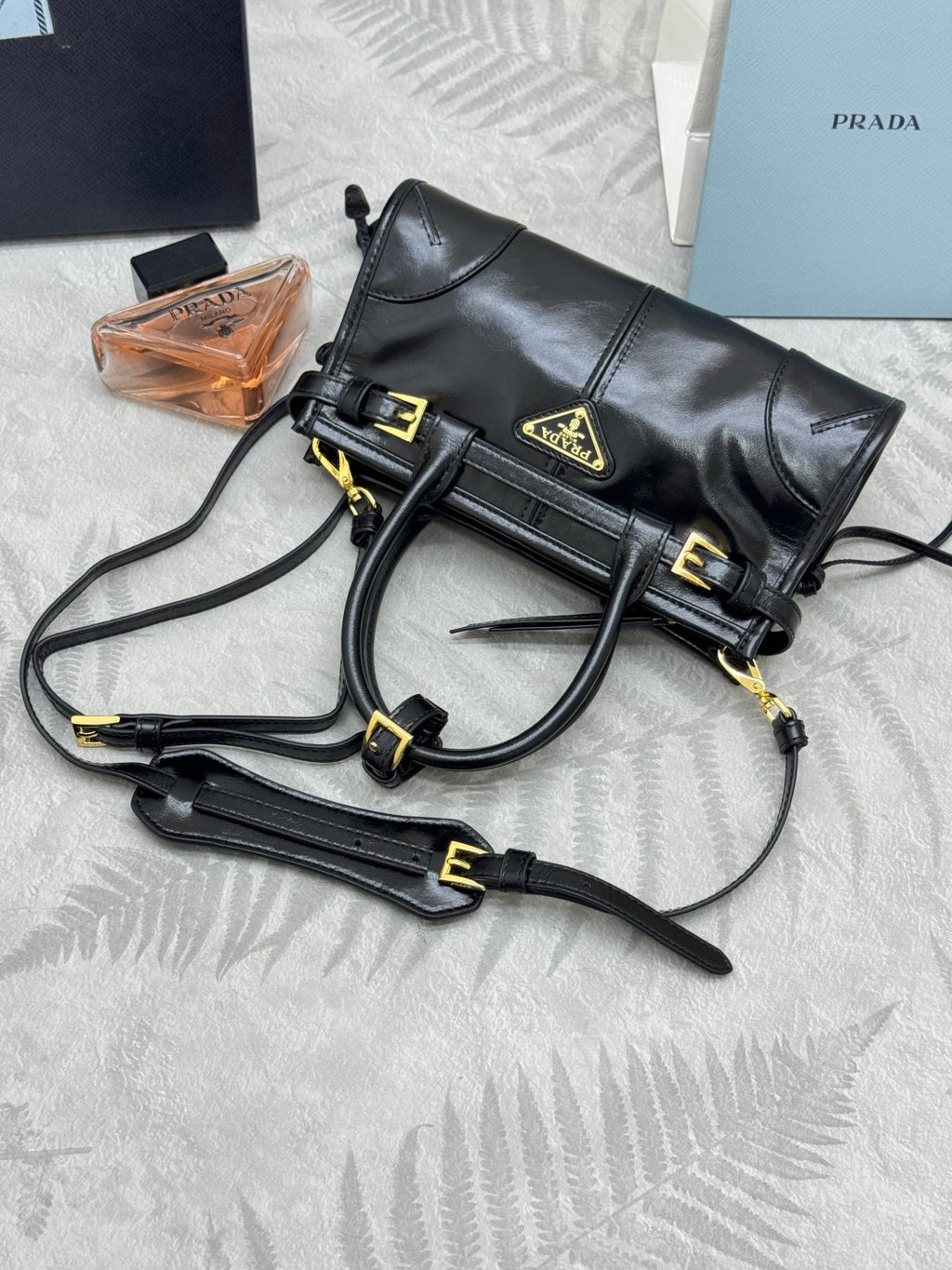 Black leather crossbody handbag with gold buckles and long shoulder strap