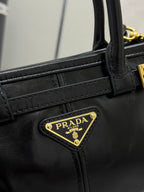 Black leather handbag close-up with gold PRADA logo plaque and stitched strap panel