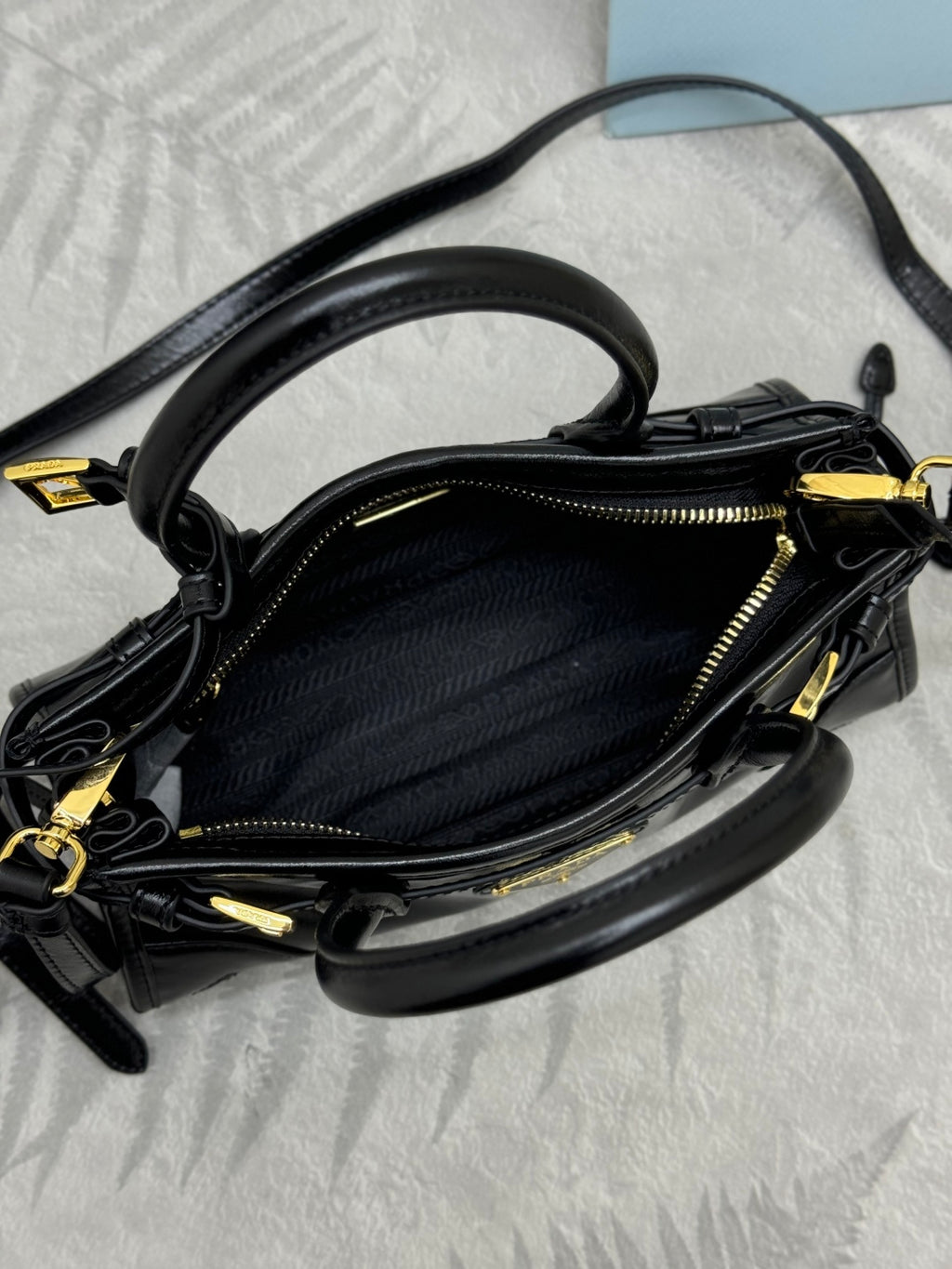 Black leather handbag interior view with gold-tone zipper and crossbody strap