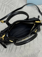 Black leather handbag interior view with gold-tone zipper and crossbody strap