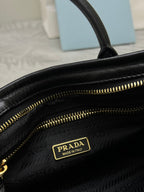 Black leather handbag close-up with gold PRADA plaque and zipper track