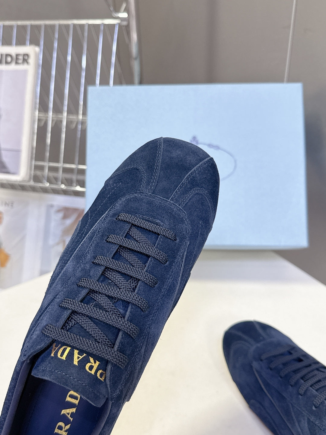 Blue suede sneaker with lace-up front and Prada logo at tongue.