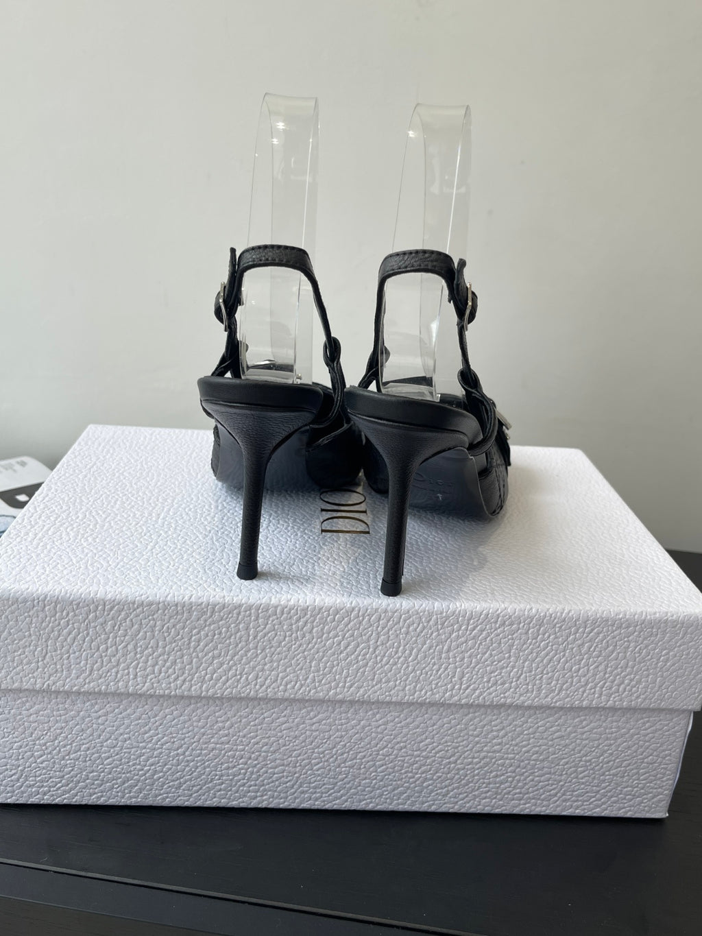 Black slingback pumps with ankle straps and stiletto heels on protective covers