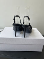 Black slingback pumps with ankle straps and stiletto heels on protective covers