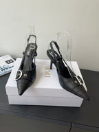 Black pointed-toe Dior slingback pumps with buckled straps and clear heel covers