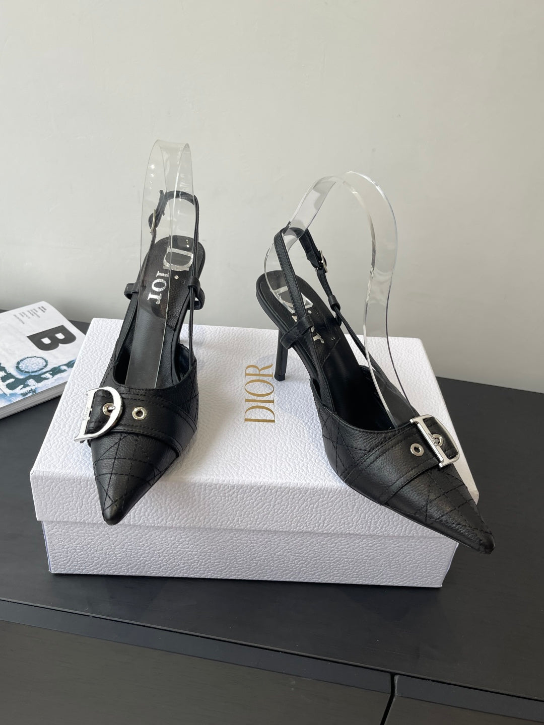 Black pointed-toe Dior slingback pumps with buckled straps and clear heel covers