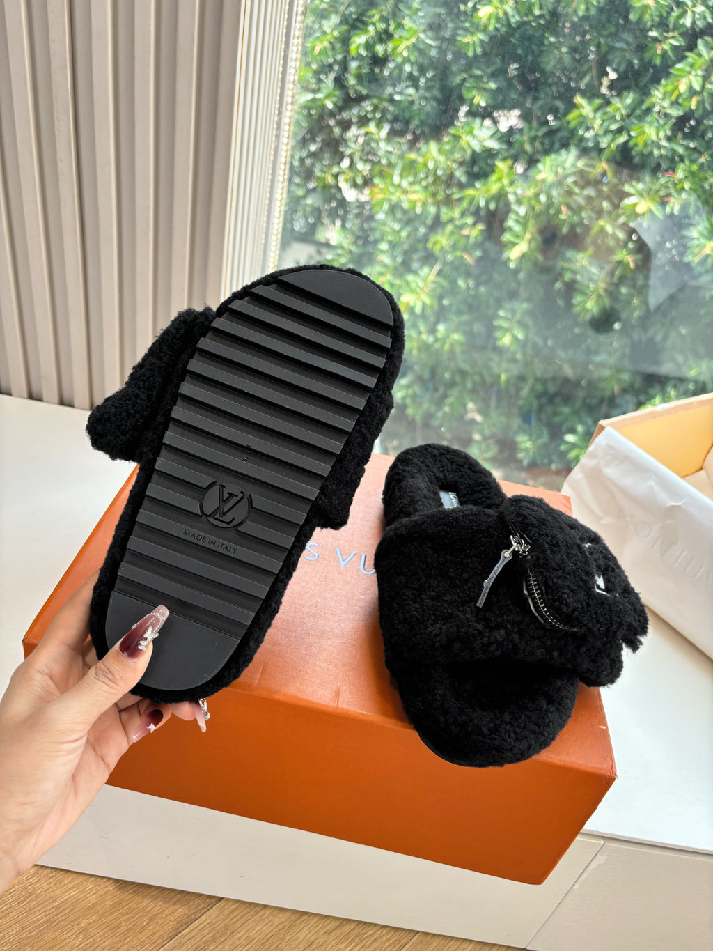 Black faux-fur mule showing ribbed rubber outsole underside