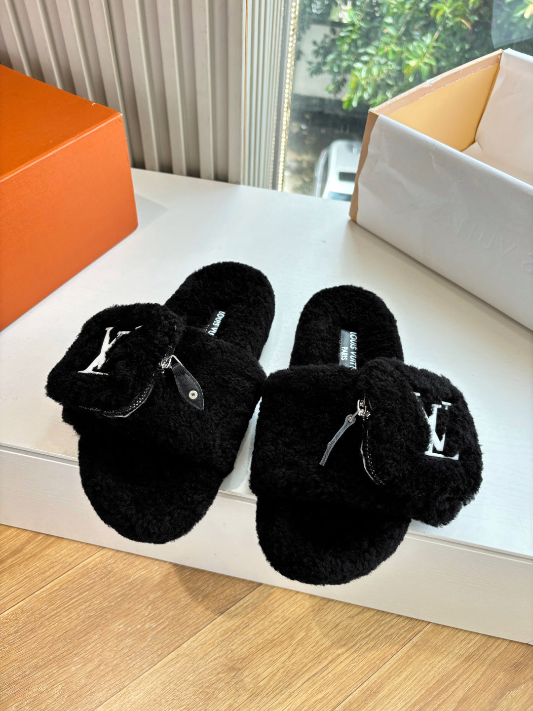 Black faux-fur slide slippers with V-logo detail on the strap