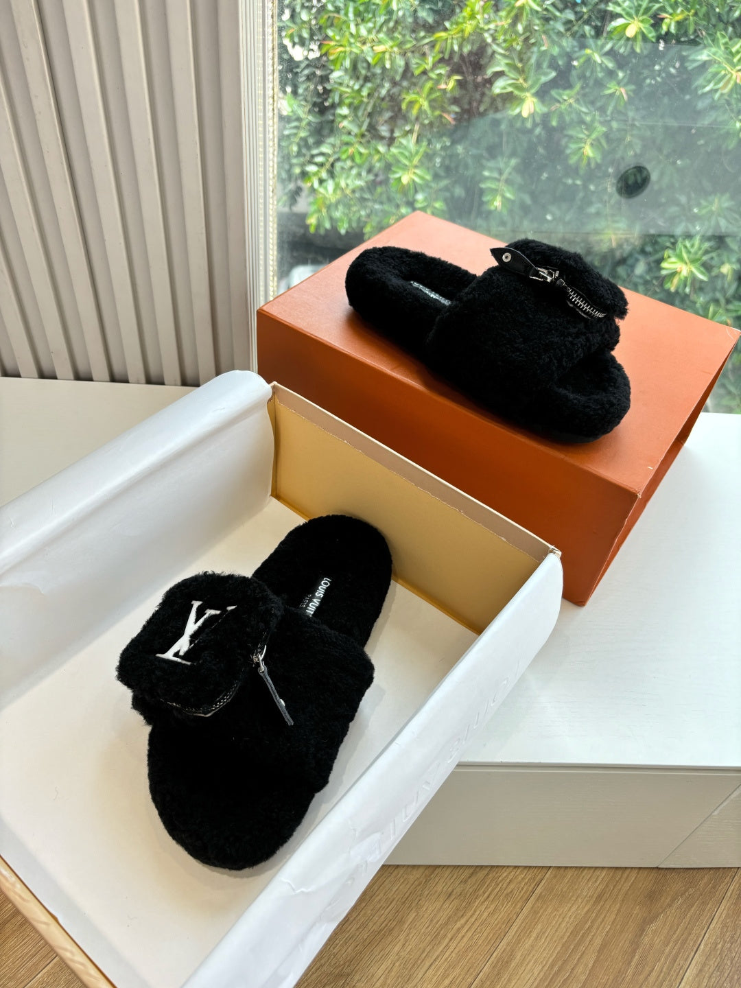 Black faux-fur slide sandals with V-logo on the top strap