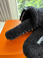 Black faux-fur sandal showing textured outsole tread and zipper detail