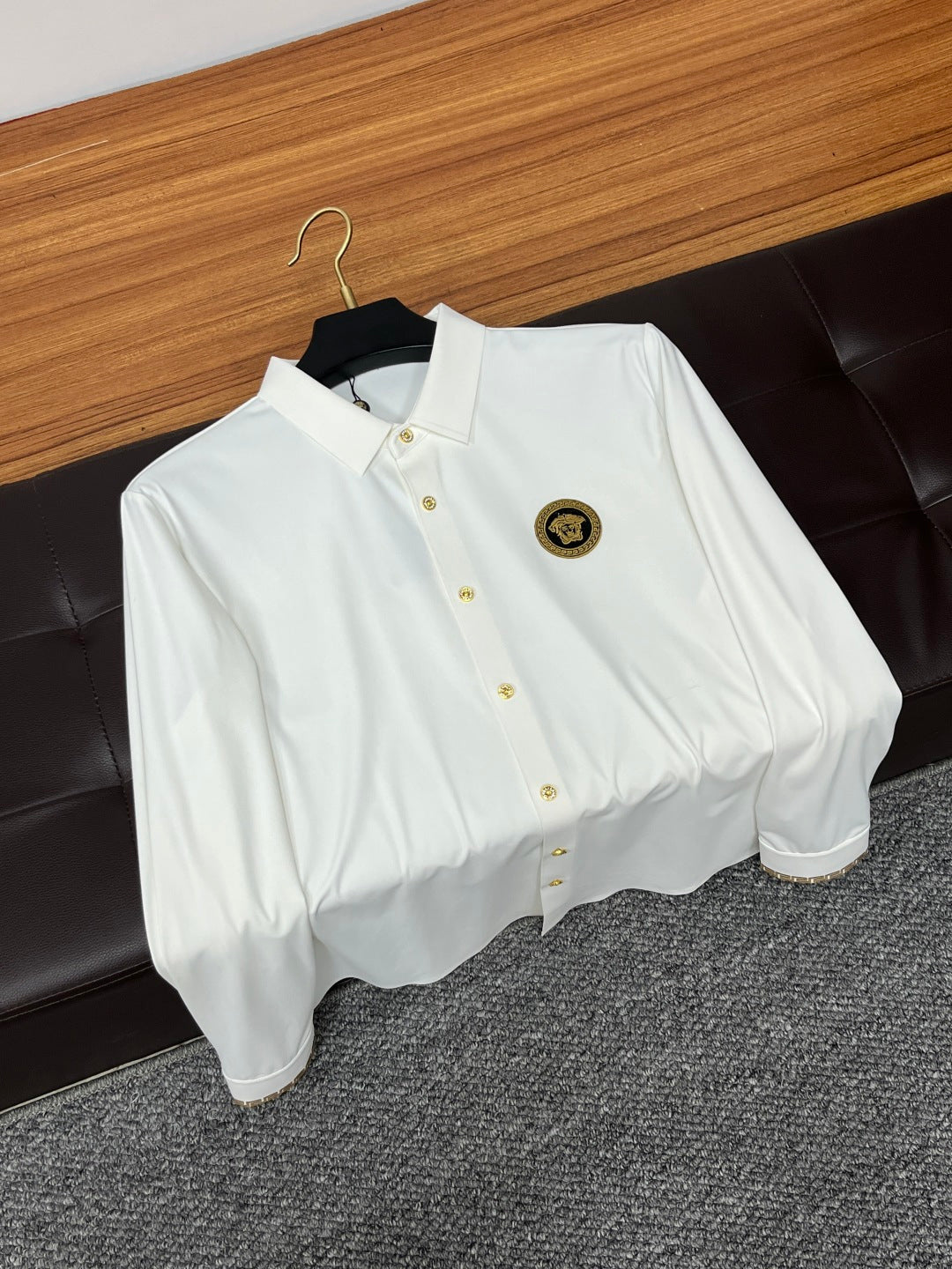 White button-up shirt on hanger with point collar and gold emblem patch
