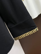 Black shirt cuff with Greek-key trim band and gold medallion button