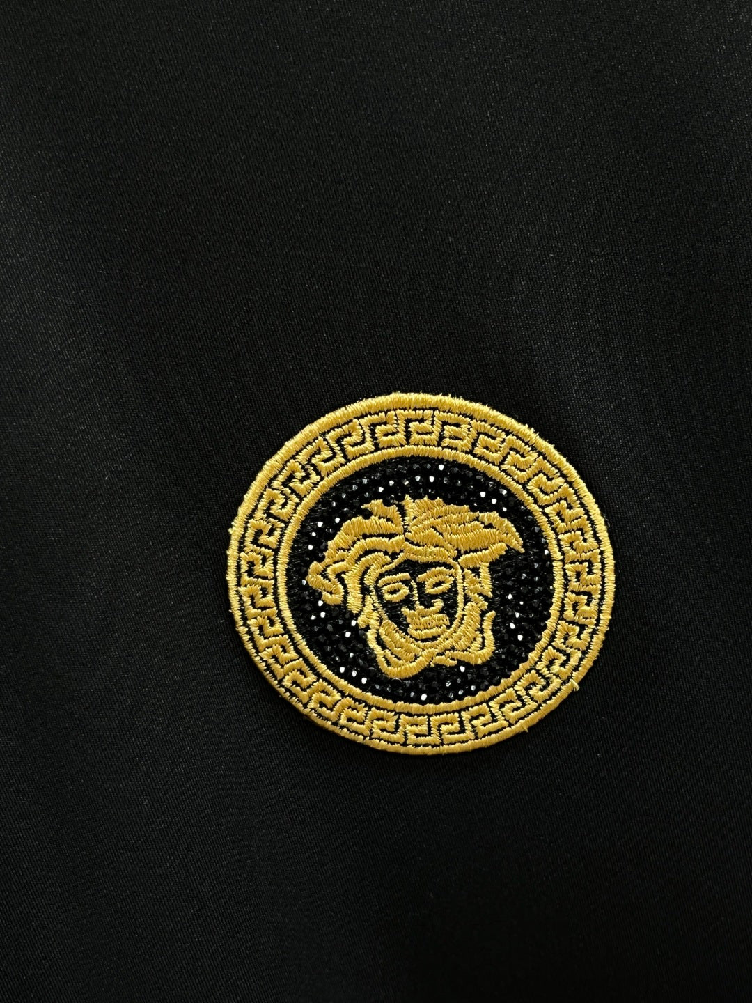 Gold embroidered medallion emblem on dark fabric