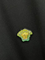 Versace embroidered lion logo patch in green and gold on black fabric