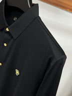 Black button-up shirt with embroidered chest logo and gold button placket