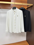 Hanging white and black button-up shirts with gold buttons and small chest emblems