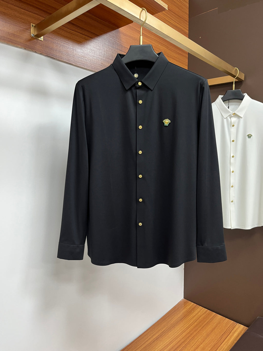 Black button-up shirt with pointed collar, gold buttons, and small chest emblem