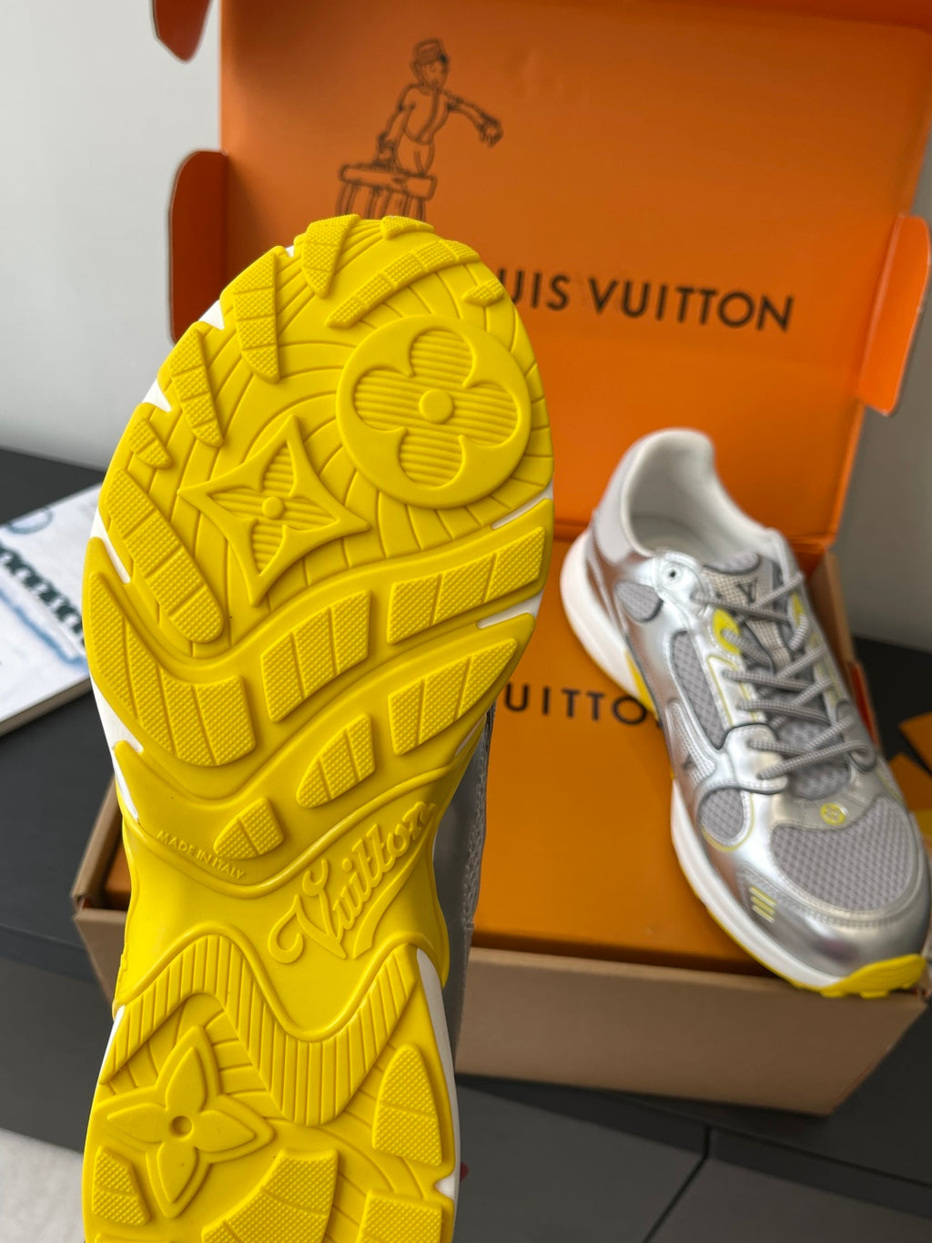 Yellow Louis Vuitton sneaker outsole with embossed logo pattern, shown beside shoe