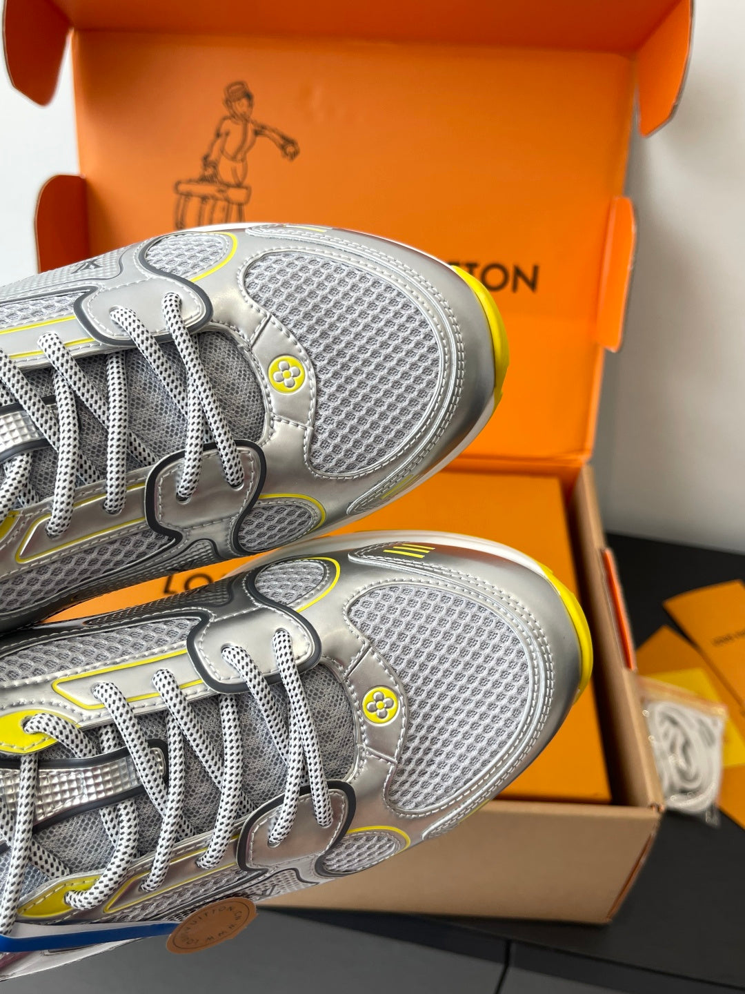 Silver Louis Vuitton sneakers close-up of textured toe, laces, and yellow edge trim