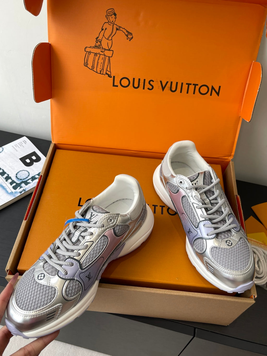 Pair of ladies' luxury sneakers in light gray with lace-up design, shown in box
