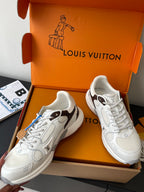 Pair of white lace-up sneakers in an open orange box, angled view with laces visible.
