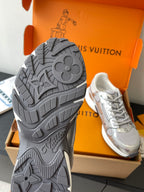 Shoe outsole view: gray textured tread on sneaker, with matching pair in box.