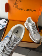 Silver sneaker pair with lace-up and padded collar, with an orange brand box.