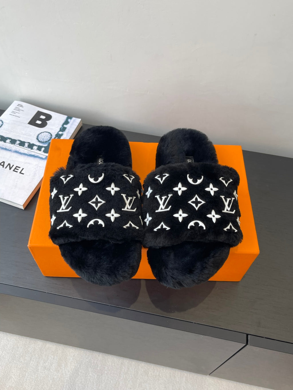 Black plush slide sandals with white monogram pattern, wide crossover straps