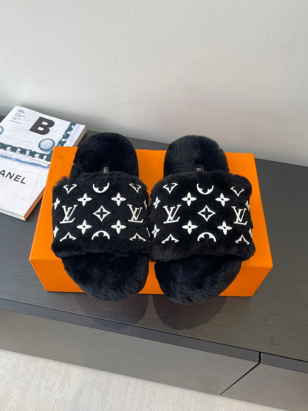 Black plush slide sandals with white monogram pattern, wide crossover straps