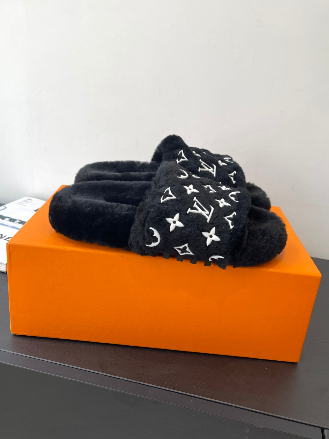 Black plush slide sandals with white monogram pattern on the upper
