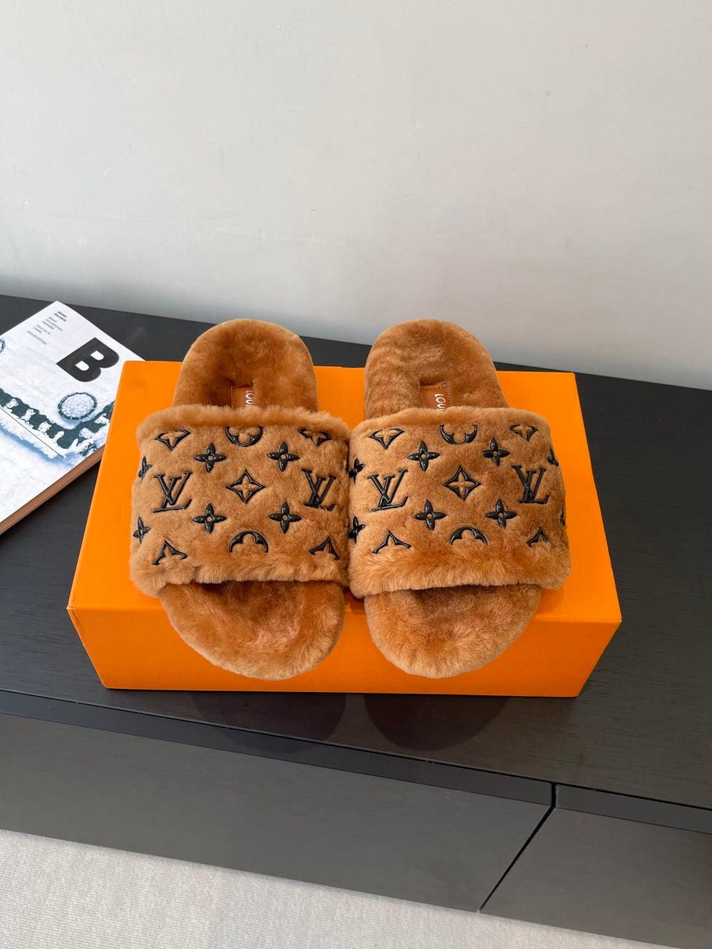 Brown fur slide sandals with dark monogram pattern and thick open toe straps.