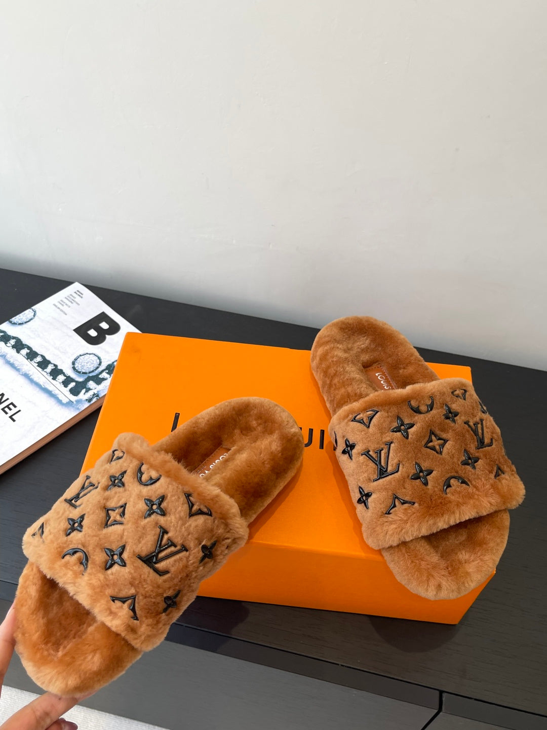 Brown fur slide sandals with dark monogram print on the strap, open toe.