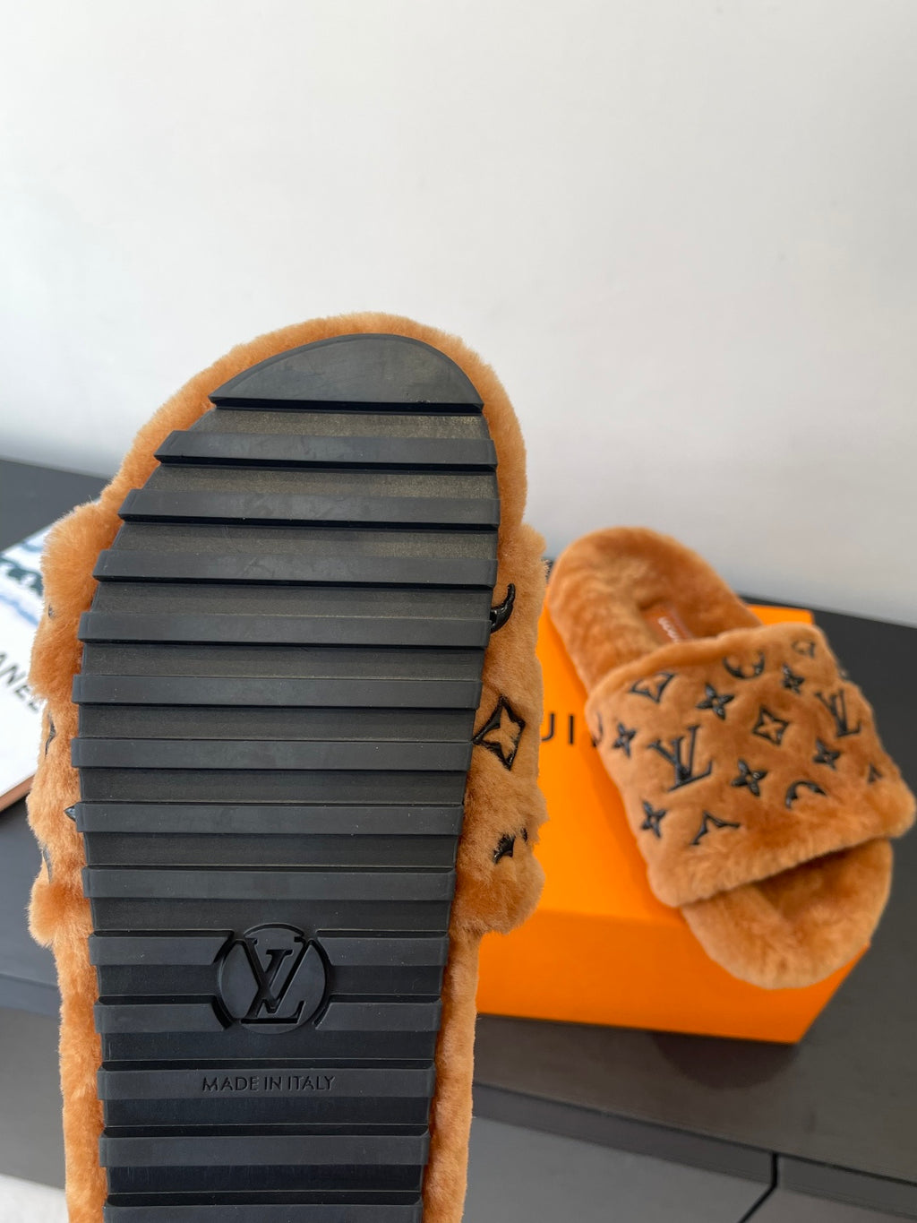 Brown fur slide sandals with dark logo outsole and cushioned upper strap.