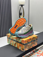 Moncler trail sneaker with beige upper, green and purple sides, blue outsole with orange tread