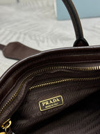 Prada brown leather bag interior close-up with gold zipper track and logo patch