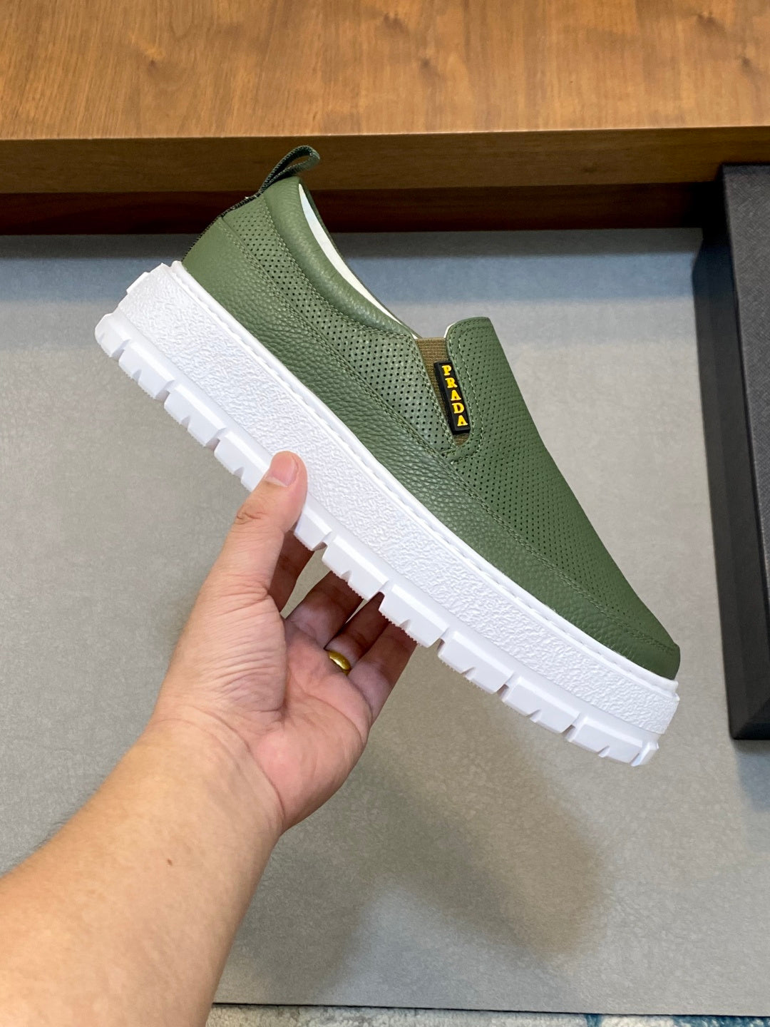 Prada unisex slip-on sneaker held in hand, green mesh upper and white sole