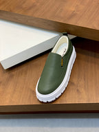 Prada unisex slip-on shoes with green upper and white treaded sole on shelf