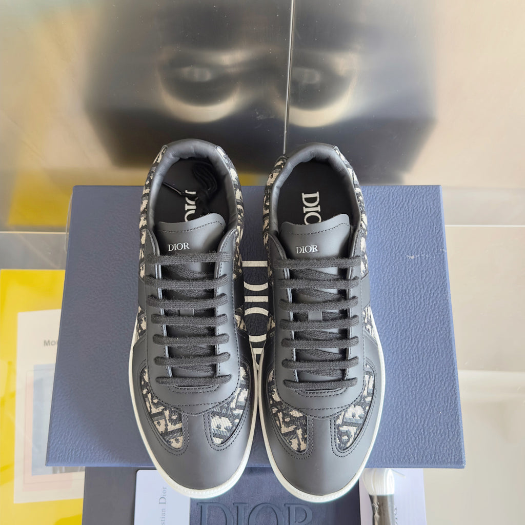 Low-top sneakers front view, dark gray with Dior monogram trim, black laces, white sole.