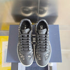 Low-top sneakers front view, dark gray with Dior monogram trim, black laces, white sole.
