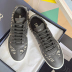 Low-top sneakers, dark gray leather with Dior monogram panels, black laces, white sole.