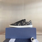 Low-top sneaker profile, dark gray with Dior monogram panels and black laces, white sole.