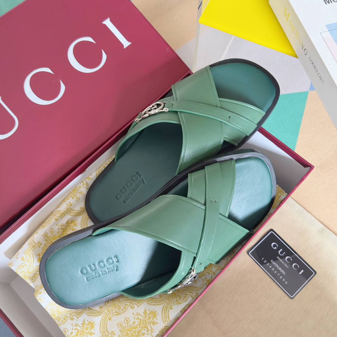 Gucci green slide sandals with crisscross straps and silver logo buckle, open toe