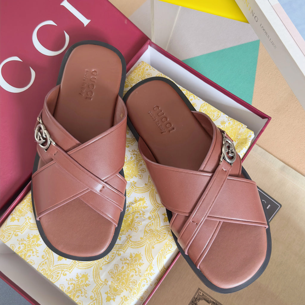 Gucci pink leather slide sandals with crisscross straps and metal logo buckle.