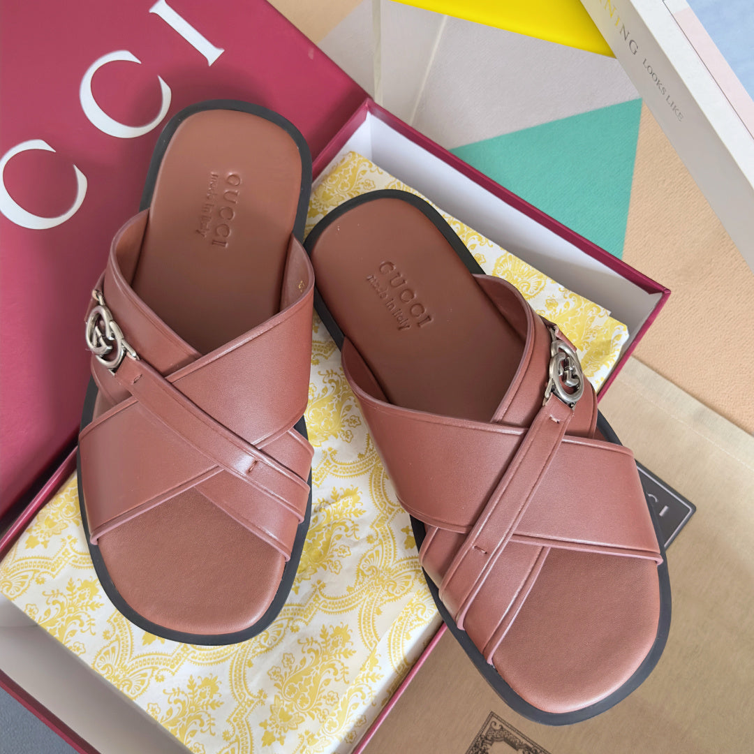 Gucci pink leather slide sandals with crisscross straps and metal logo buckle.