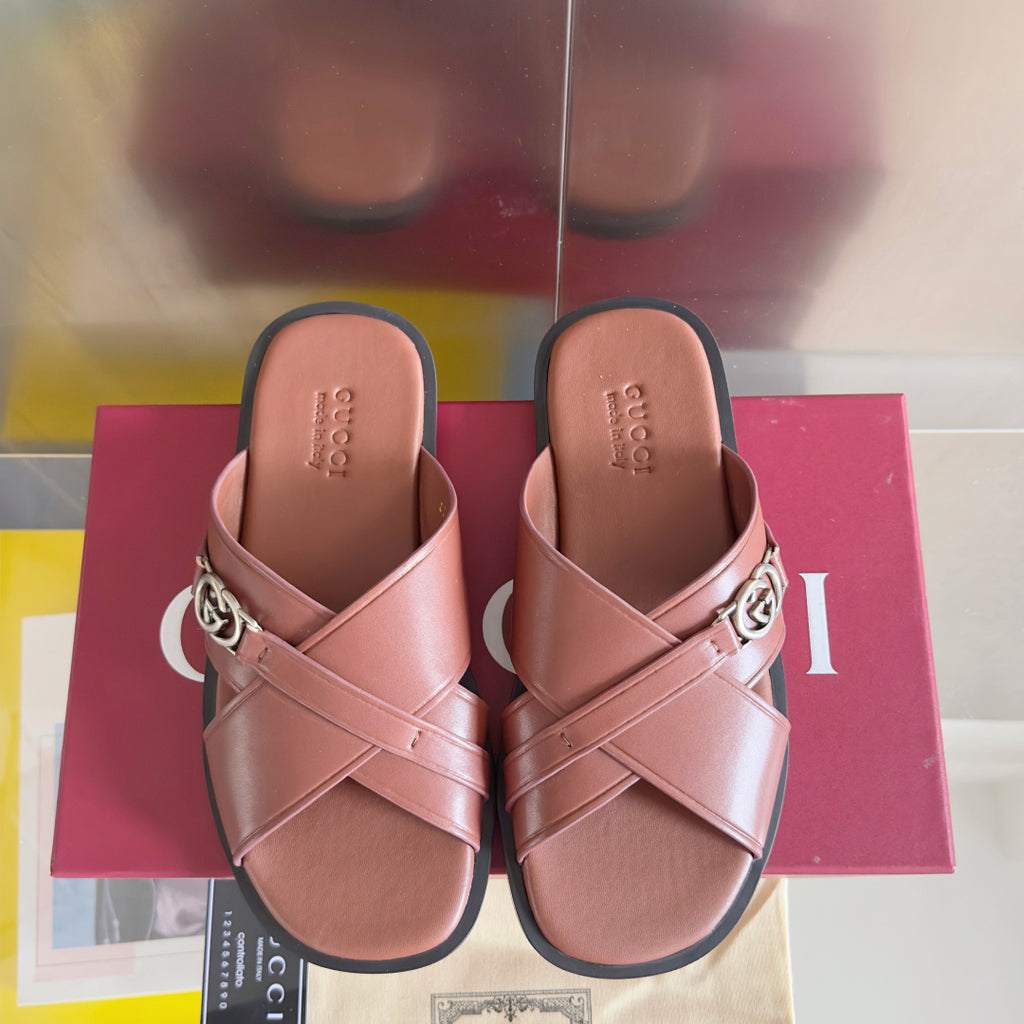 Gucci pink leather slide sandals with X straps and metal GG logo buckle hardware.
