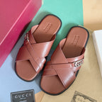 Gucci pink leather slide sandals with crisscross straps and metal GG logo buckle.
