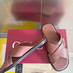 Gucci pink slide sandals with crisscross straps and metal GG buckle on upper.