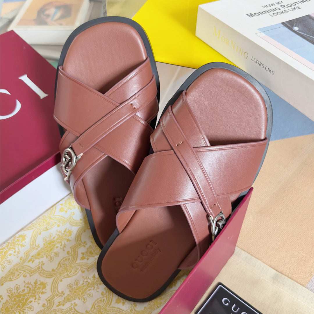 Gucci pink leather slide sandals with cross straps and metal GG logo buckle detail.