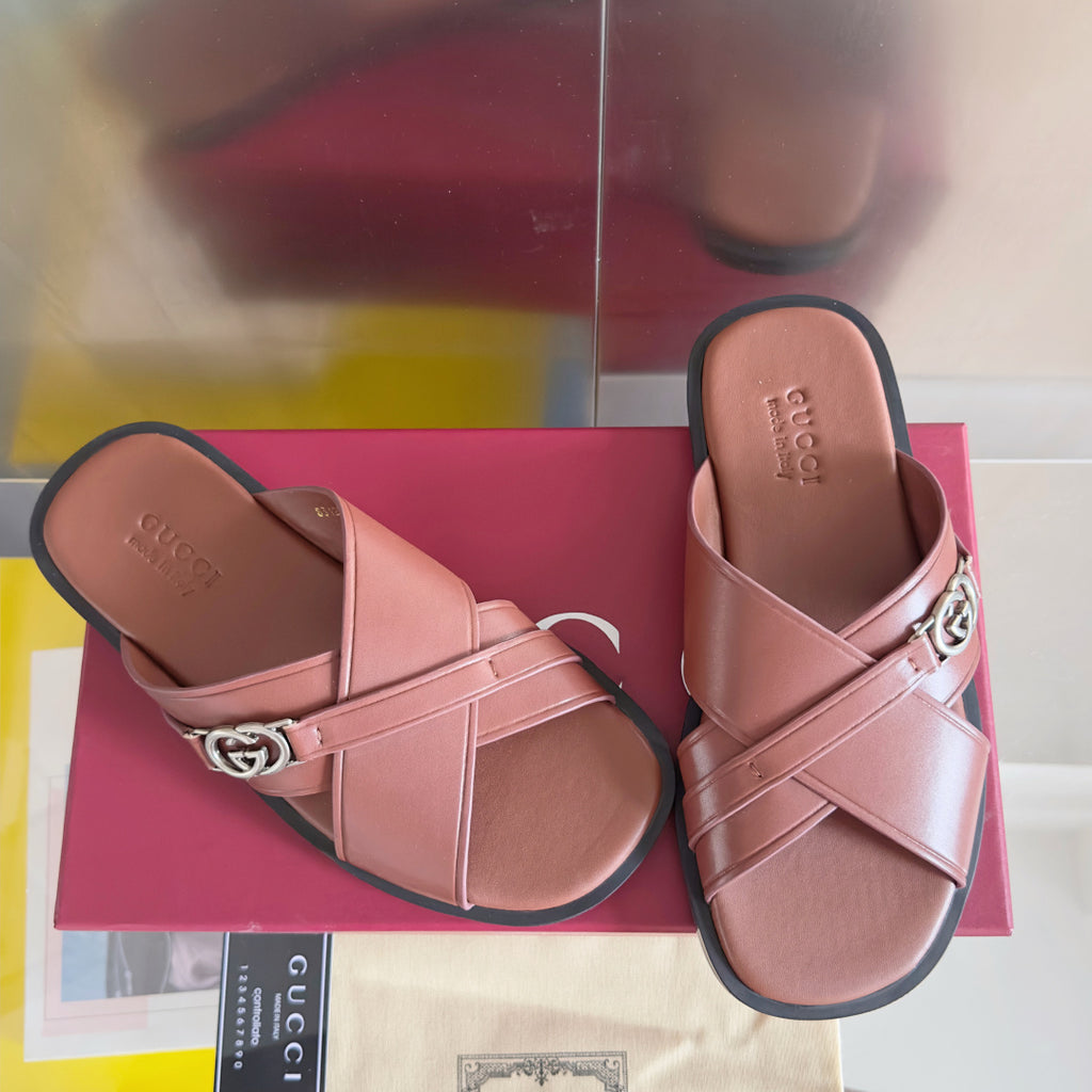 Gucci pink leather slide sandals with wide straps and GG logo metal buckle.