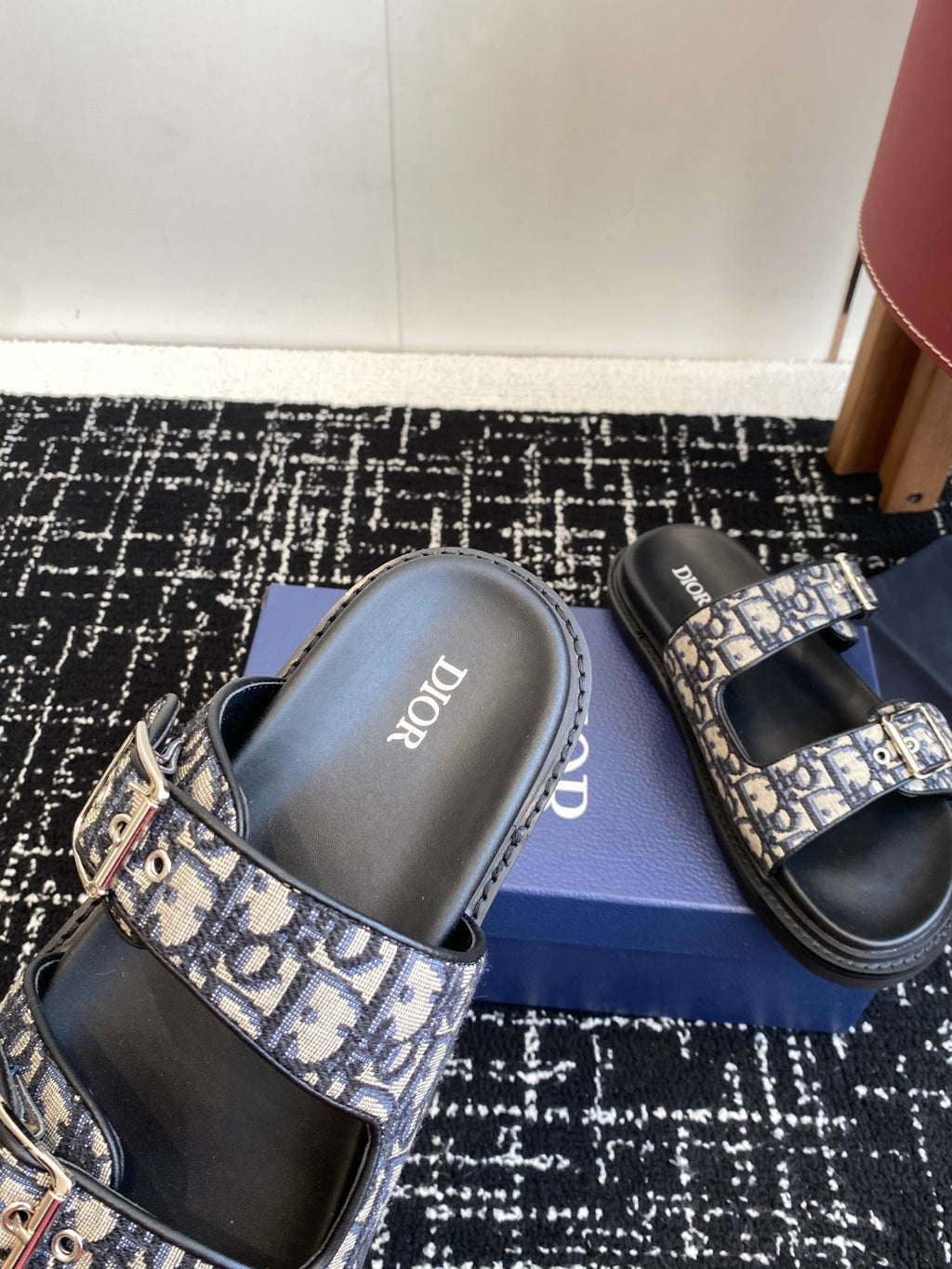 Dior sandals close-up with blue patterned strap over black footbed and insole branding